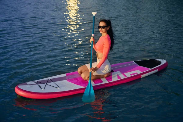 Yemek masasında elinde kürekle yüzen bayan sporcu.