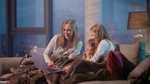 Csinos lányok és az anyjuk ül a kanapén laptoppal — Stock videók