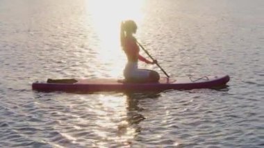 Gün batımında yemek yiyen bir kadının yan görüntüsü