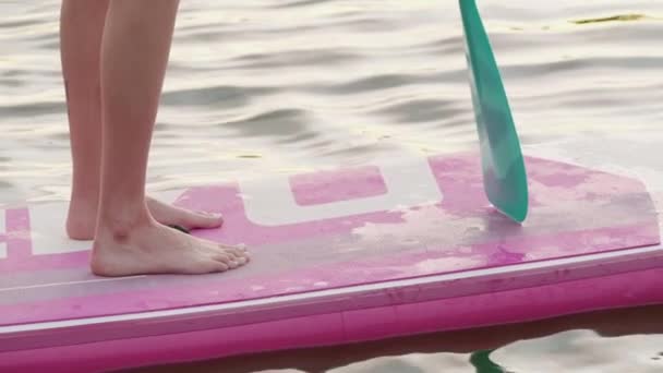 Крупним планом жінка з босоніж плаває на дошці — стокове відео