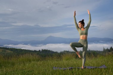 Esmer kadın tek bacağının üstünde duruyor..