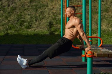 Gömleksiz beyaz vücut geliştirici açık havada şınav çekiyor.