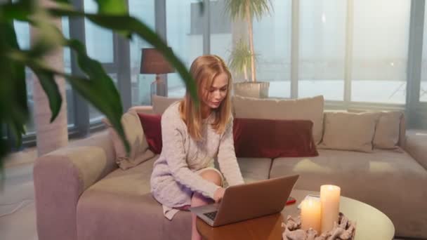 Jonge vrouw met laptop tijdens de avonduren thuis — Stockvideo