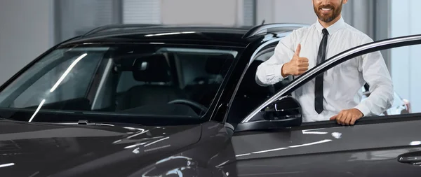 Geschäftsmann zeigt beim Autokauf im Salon Daumen hoch — Stockfoto