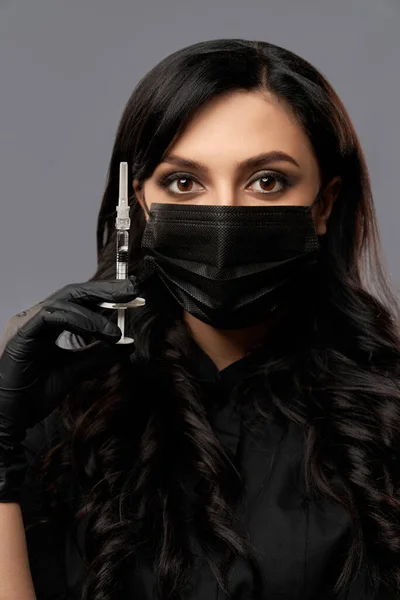 Esteticista feminina em máscara facial e luvas segurando seringa — Fotografia de Stock