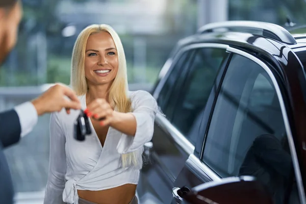 Gerente de coche dando llaves a comprador femenino en sala de exposición —  Fotos de Stock