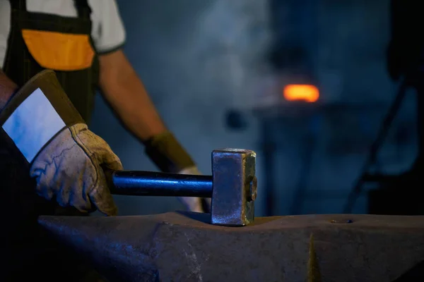 Close up of blacksmith in gloves using hammer for work — Stock Photo, Image