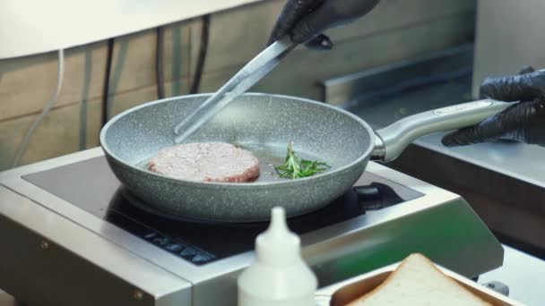 Hombre con guantes poniendo carne de hamburguesa cruda en la sartén calentada — Vídeos de Stock