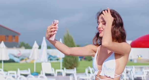 Приятная женщина в купальнике делает селфи на смартфоне — стоковое видео