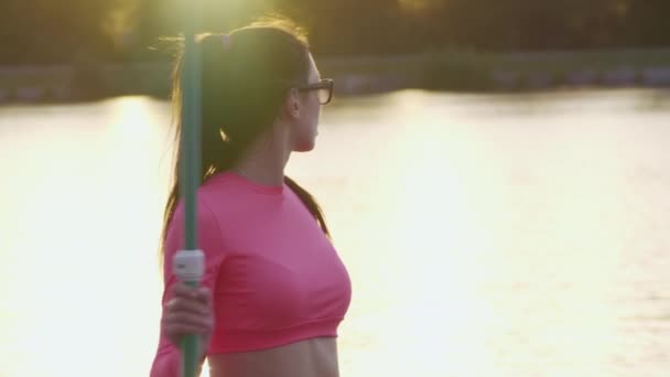 Mujer disfrutando de la puesta de sol durante el verano sup embarque en el lago — Vídeos de Stock