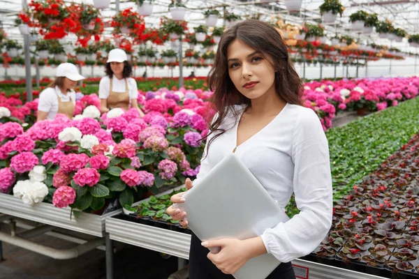 Young woman working in modern greenhouse with laptop. — Stock Photo, Image