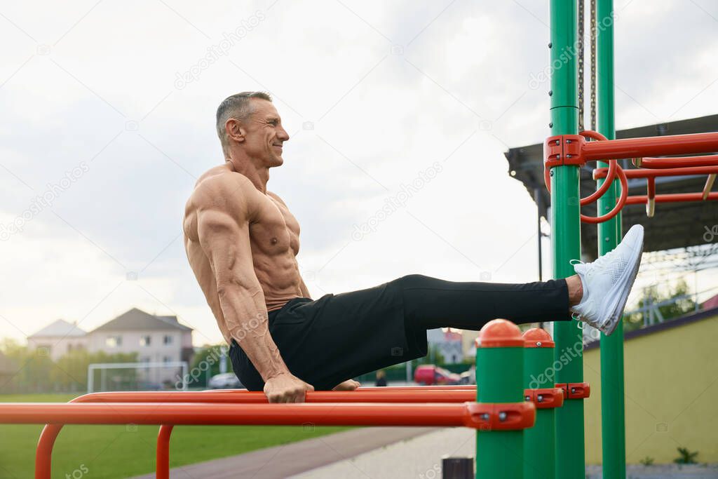 Handsome man with bare torso doing push ups outdoors