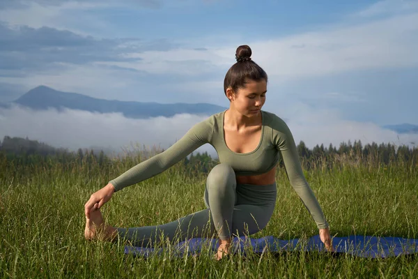 Kvinna i sportkläder som utövar yoga bland naturen — Stockfoto