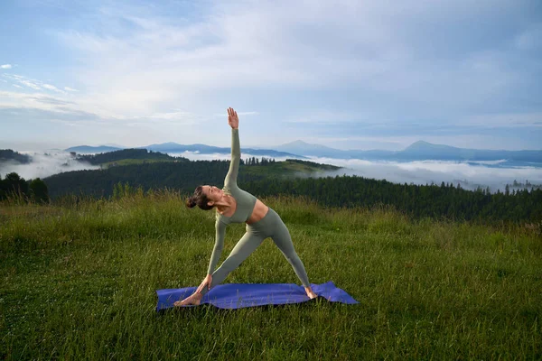 Молодая женщина в спортивной одежде практикует йогу на природе — стоковое фото
