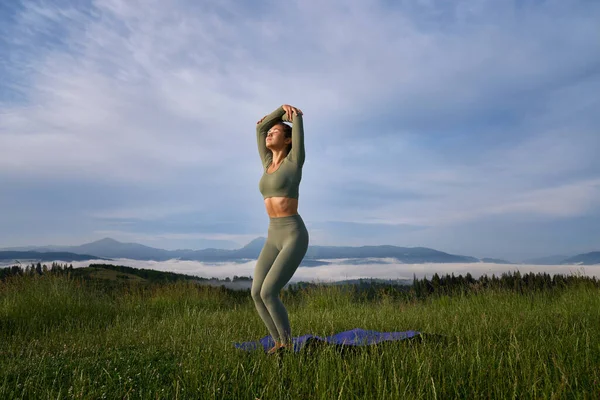 Donna in abiti sportivi facendo esercizi di yoga sulla natura — Foto Stock