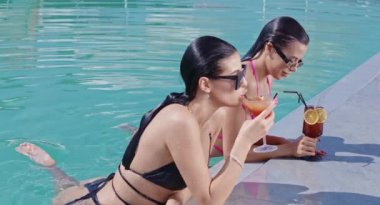 Havuzda yüzerken kokteyl içen sevimli kadınlar.