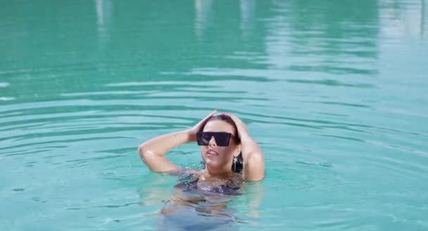 Mujer feliz en gafas de sol y bikini nadando en la piscina — Vídeos de Stock