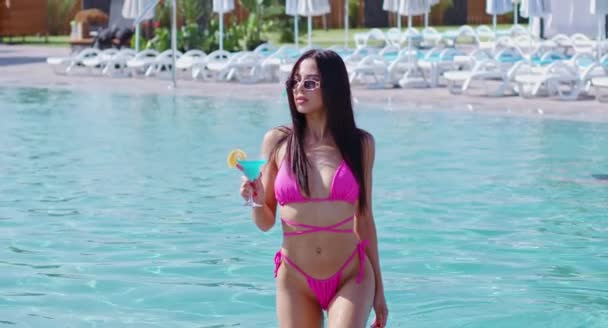 Kvinna i bikini poserar i pool med cocktail i handen — Stockvideo