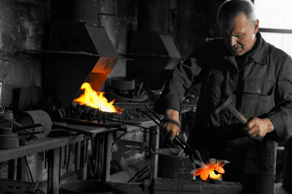 Дорослий чоловік працює з гарячим металом біля опалювальних приладів . — стокове фото