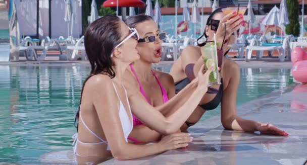 Vidám nők medencében úsznak és koktélokat isznak — Stock videók