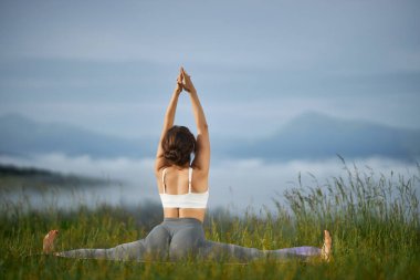 Girl sitiing in yoga pose in nature. clipart