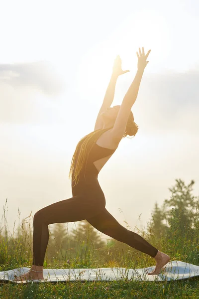 Mädchen tritt in der Natur auf Yogamatte. — Stockfoto