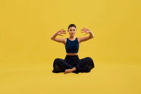 Молода жінка сидить на підлозі, роблячи йогу . — стокове фото