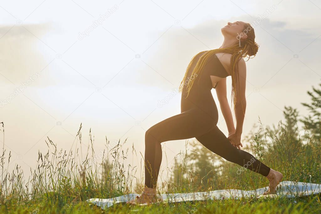 Sporty female practicing yoga in nature.