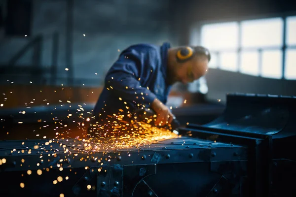 Průmyslový dělník zpracovávající kov s úhlovou bruskou — Stock fotografie