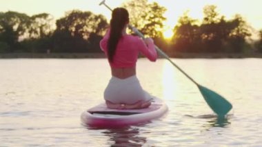 Yemek masasında oturan ve uzun kürekle kürek çeken bir kadın