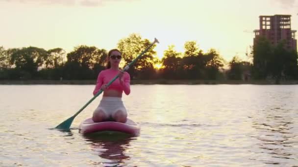 운동복을 입고 노를 타며 수영하는 젊은 여자 — 비디오