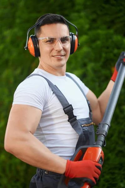 Gardener standing near hedge with electric trimmer in hands — Stock Photo, Image