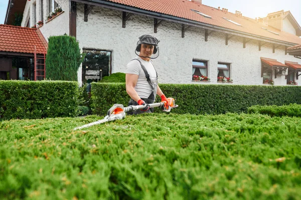 Jardinero usando trimmer eléctrico para formar arbustos — Foto de Stock