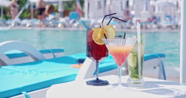 Drei Cocktailgläser stehen am Pool auf dem Tisch — Stockvideo