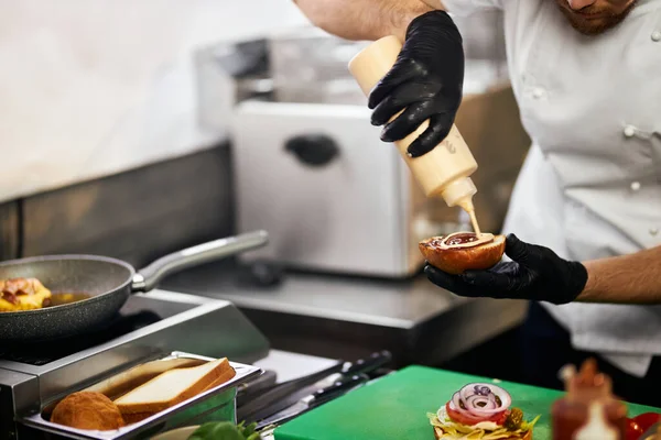 Versare la salsa maionese su un gustoso hamburger. — Foto Stock