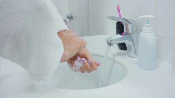 Giovane donna in accappatoio bianco lavarsi le mani con sapone. — Video Stock