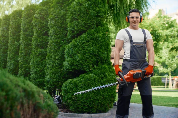 Uomo che tiene trimmer elettrico mentre in piedi in giardino — Foto Stock