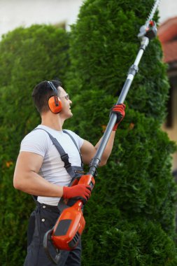 Kafkas işçi tulumlu arka bahçede çit buduyor.