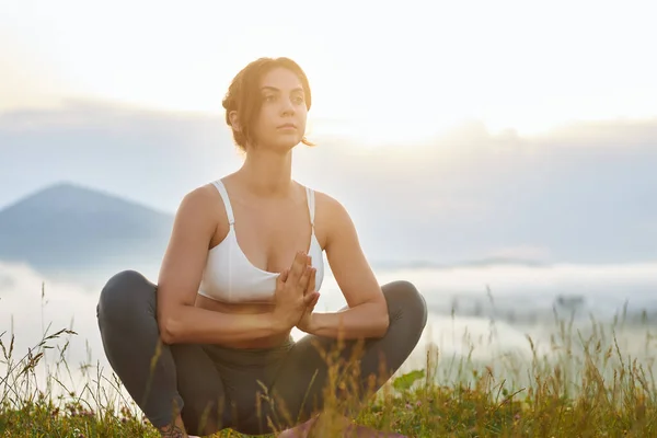 Young girl sitting in lotos pose in mountains. — Foto Stock