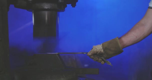 Blacksmith long iron stick by hands under press holding. — Stock video