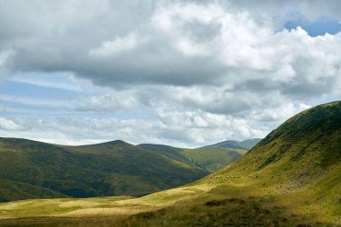 Çimenli güneşli vadi dağ yamaçlarının arasında uzanıyordu..