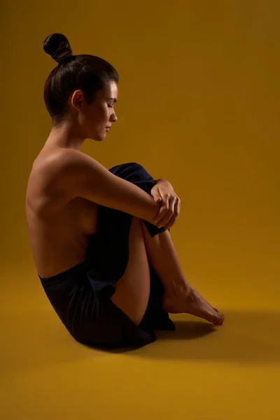 Dívka sedící na podlaze, držící nohy pažemi. — Stock fotografie