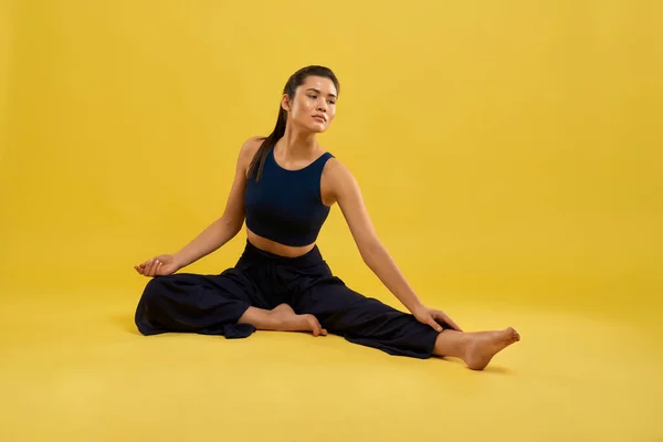 Sporty girl sitting on floor, stretching. — kuvapankkivalokuva