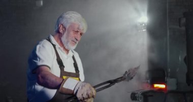 Blacksmith forging metalwork in smithy.