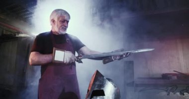 Yaşlı demirci şövalye ve savaşçı için zırh dövüyor..