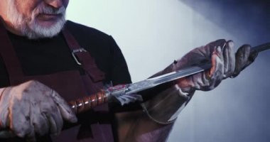 Blacksmith looking at sword, hilt holding.