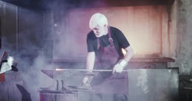 Demirci uzun demir çubuk açık ateş almak.