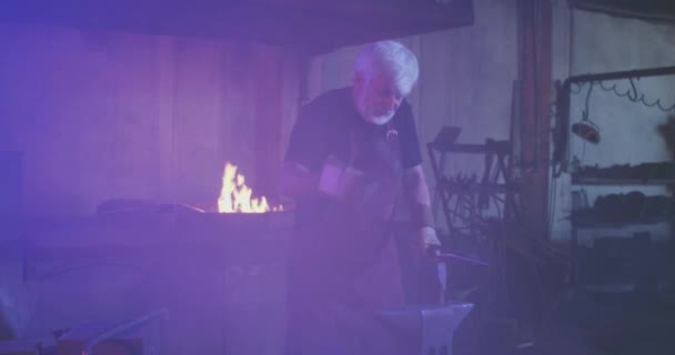Blacksmith working in dark smithy. — Stock video