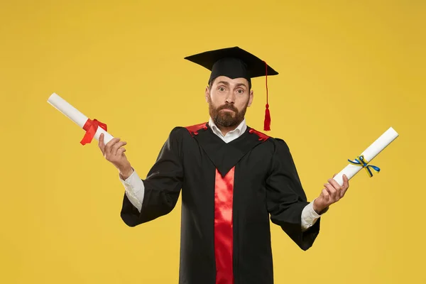 Male student holding two diplomas, standing mixed up. — Stockfoto