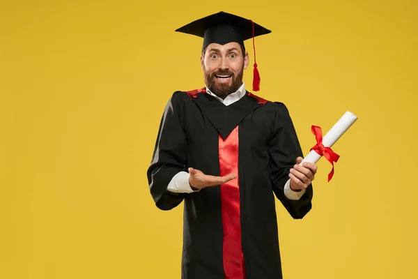 Stdudent standing, holding diploma, surprised. — Fotografia de Stock